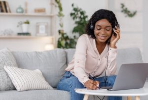 Young black woman studying online with laptop at home and taking notes